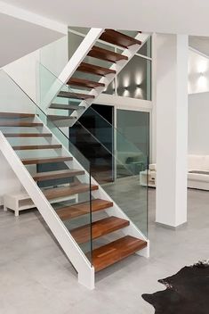 a modern staircase with glass railing and wood handrails in a living room area