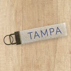 a keychain with the word tampa on it sitting on top of a wooden table