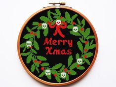 a cross stitch christmas wreath with skulls and holly