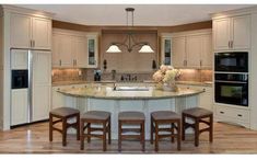 a large kitchen with an island in the middle and three stools at the center