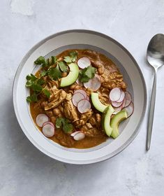 a bowl filled with meat and vegetables next to a spoon