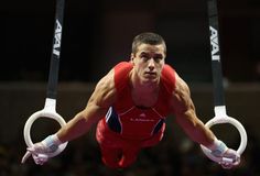 a man in red shirt doing aerial tricks on rings