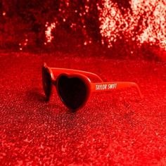 red sunglasses with the words taylor street printed on them sitting in front of a glitter background