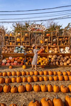 a woman standing in front of a display of pumpkins