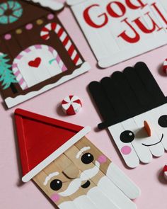 paper cutouts with santa claus and other decorations on a pink surface, including candy canes