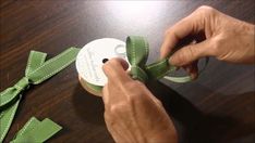 someone is tying a green ribbon on a wooden table