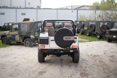 several jeeps and trucks are parked in the dirt