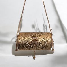 Introducing our exquisite antique handmade brass clutch, a timeless accessory that seamlessly blends artistry and functionality. Crafted with meticulous attention to detail, this clutch boasts a unique cylinder shape, measuring 6.1 inches in length. The exterior showcases intricate metalwork, reflecting the skilled craftsmanship of yesteryears. Open the clutch to reveal a luxurious velvet interior, providing a soft and sumptuous backdrop for your essentials. The combination of antique metal and