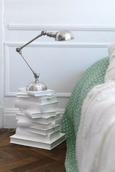 a stack of books sitting on top of a wooden floor next to a metal lamp