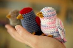 small crocheted birds sitting on the palm of someone's hand in front of them