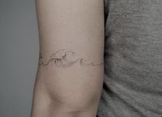 a woman's arm with a wave tattoo on the left side of her arm