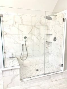 a walk in shower sitting next to a white tiled wall and floor with a glass door