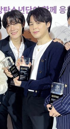 three young men holding up their awards in front of a sign