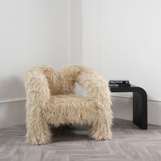 a furry chair sitting on top of a hard wood floor next to a black table