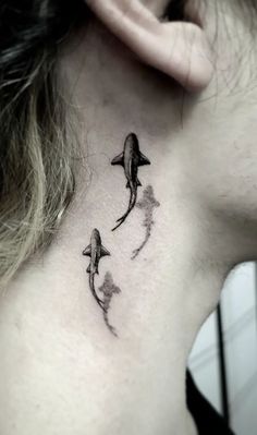 a woman's neck with two dolphins on it