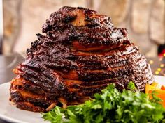 a large piece of meat sitting on top of a white plate next to a salad