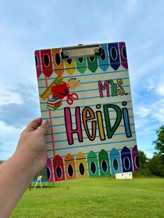 a hand holding up a notebook with the words my miss heidi written on it