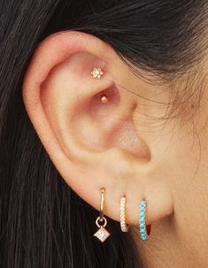 a close up of a person's ear with two different colored stones on it