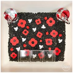 red and white flowers are placed on the black seed trays with silver spoons