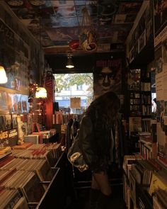 a woman standing in front of a book store filled with lots of books and cds