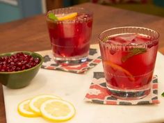 two glasses of cranberry lemonade sit on a cutting board