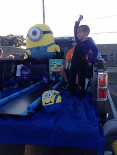 two children are sitting in the back of a pick up truck with characters on it