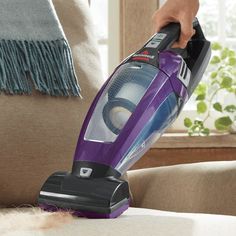 a person using a vacuum cleaner on a couch