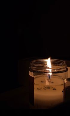 a lit candle in a jar on a table