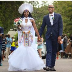 a man and woman walking down the street in wedding attire with hats on their heads