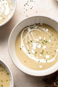 three white bowls filled with soup on top of a table