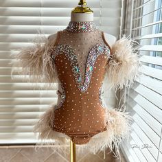 a mannequin with feathers and sequins on display in front of a window