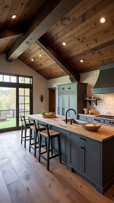 a kitchen with wooden floors and an island in the middle, surrounded by windows that look out onto a grassy field