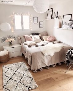 a small bedroom with white walls and wooden flooring is decorated in neutral colors, including pink