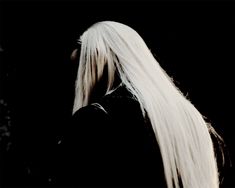 a woman with long white hair standing in the dark