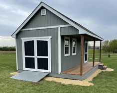 a small gray shed sitting on top of a lush green field