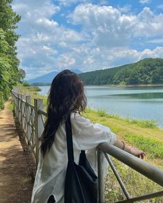 a woman standing on a bridge looking at the water