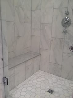 a shower with white marble tile and hexagonal tiles