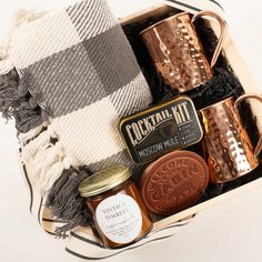 a gift box containing two mugs, a bottle of whiskey and some other items