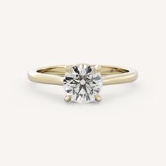 a yellow gold engagement ring with a round brilliant cut diamond in the center, on a white background