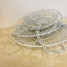 three metal baskets sitting on top of a table covered in white lace and silver chains