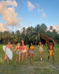 several people walking in the grass with surfboards