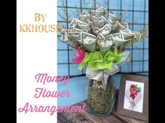 a vase filled with money sitting on top of a wooden table next to a frame