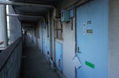 an empty hallway with blue doors and signs on the door, in front of a building