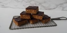 several pieces of chocolate fudge cake on a cooling rack next to a marble counter top