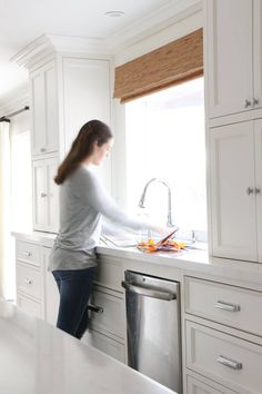 a woman is standing at the sink in her kitchen and she is washing oranges