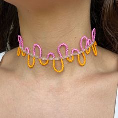 a woman wearing an orange and pink necklace with beads on it's back neck