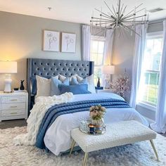 a bedroom decorated in blue and white with a chandelier