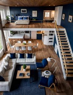 an aerial view of a living room and kitchen area with blue walls, wood flooring and white couches