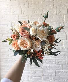 a woman holding a bouquet of flowers in front of a brick wall