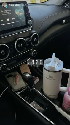 the interior of a car with coffee cups and other items on the dash board in front of it